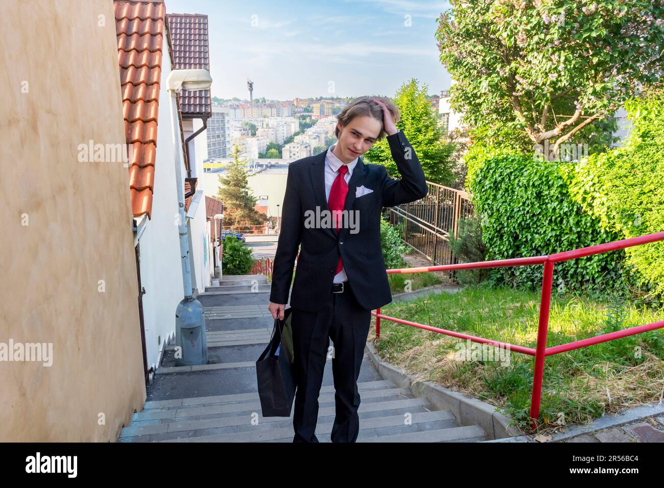 Ein Teenager in schwarzem Anzug geht gleich von zu Hause, um eine Sekundarschulabschlußprüfung zu bestehen Stockfoto