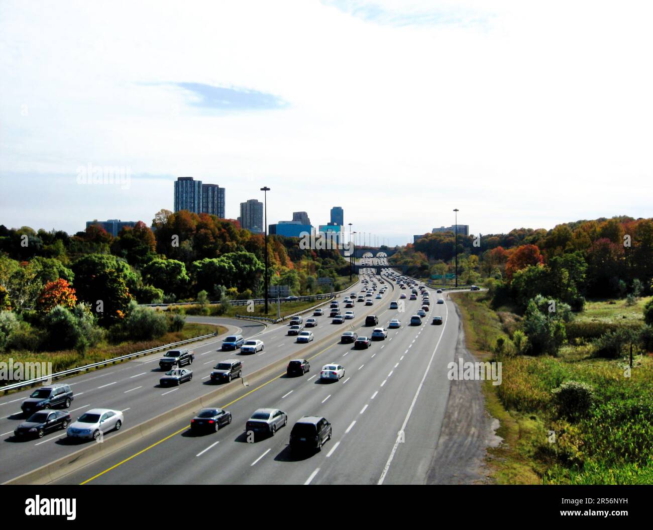 Geschäftiger Verkehr tagsüber zu Stoßzeiten. Sechsspuriger Don Valley Parkway Highway in Toronto. Schwindende Perspektive. Mehrstöckige Wohngebäude weit entfernt Stockfoto
