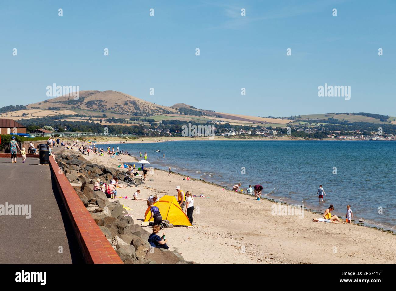 Leute genießen einen heißen Tag am Leven Beach mit Largo Law im Hintergrund, Fife, Schottland. Stockfoto