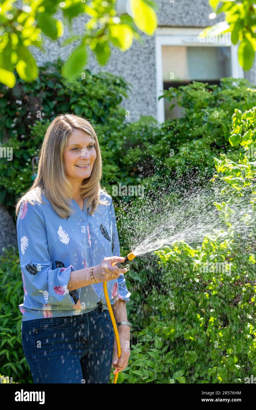 Frau, die den Garten mit Schlauch bewässert Stockfoto