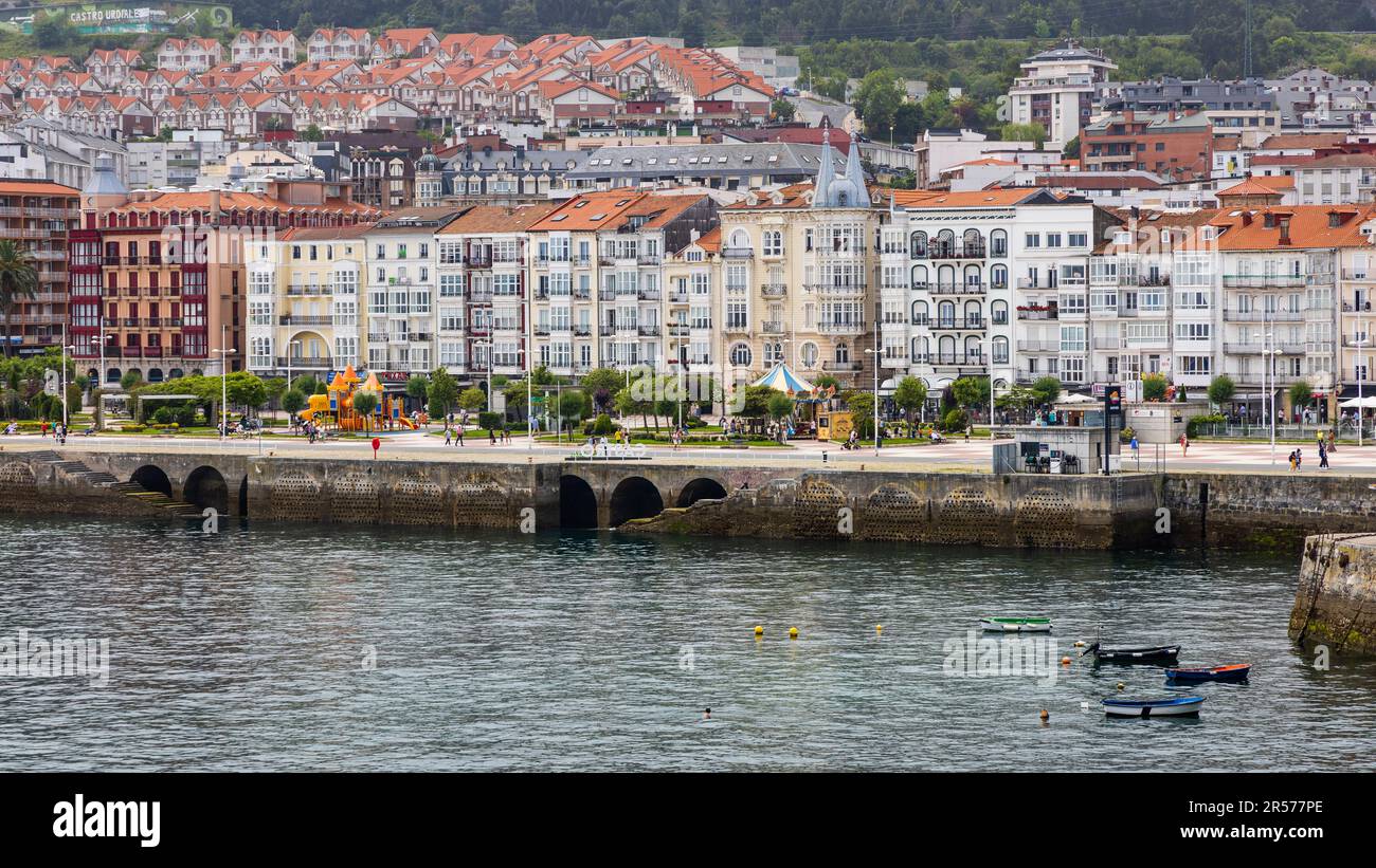 Blick auf die farbenfrohen Gebäude mit lebendigen Fassaden entlang der Uferpromenade mit Blick auf das glitzernde Wasser des Kantabrischen Meeres. Castro-Urdiales, Stockfoto