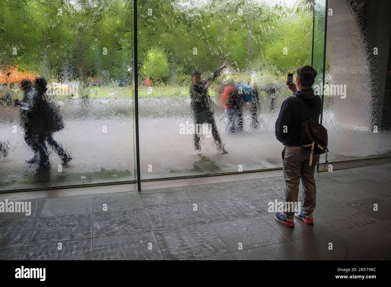 Ein Besucher fotografiert seinen Freund durch die Waterwall in der National Gallery of Victoria, Melbourne, Australien Stockfoto