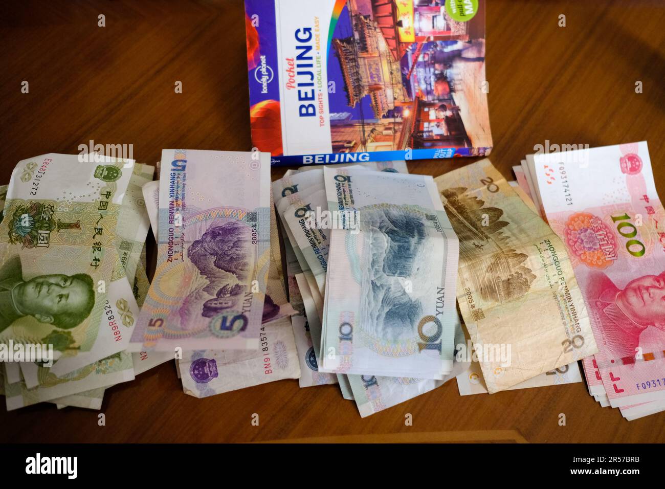 Chinesisches Geld (Noten) auf einem Tisch zusammen mit einem Lonely Planet Reisebuch über Peking Stockfoto