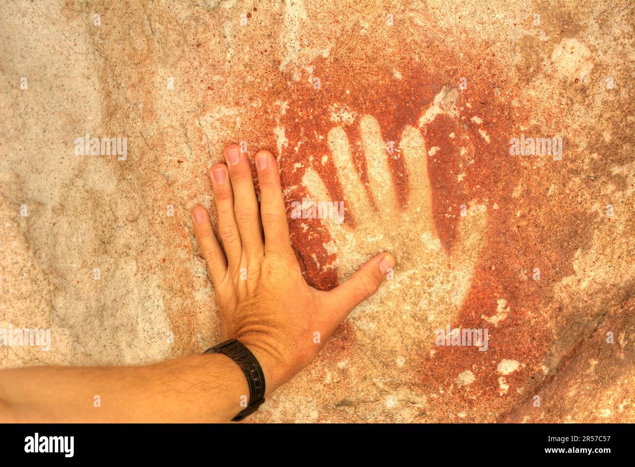 Die Hand eines Mannes berührt einen alten Handabdruck in Cueva de las Manos in der Provinz Santa Cruz, Argentinien Stockfoto
