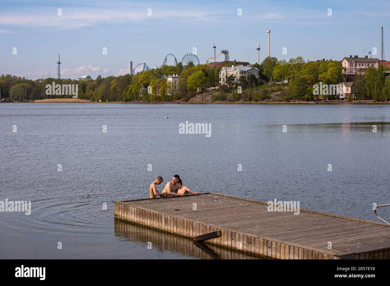 Teenager-Jungs stehen im kalten Wasser am Pier. Töölönlahti Bay, Helsinki, Finnland. Stockfoto