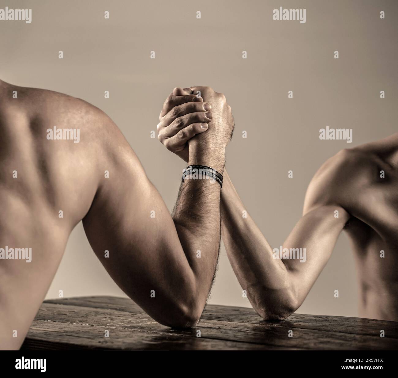 Die Hände zweier Männer umklammerten Arm-Wrestling, stark und schwach, ungleiche Übereinstimmung. Arm-Wrestling. Arme-Wrestling dünne Hand, großer starker Arm im Studio Stockfoto
