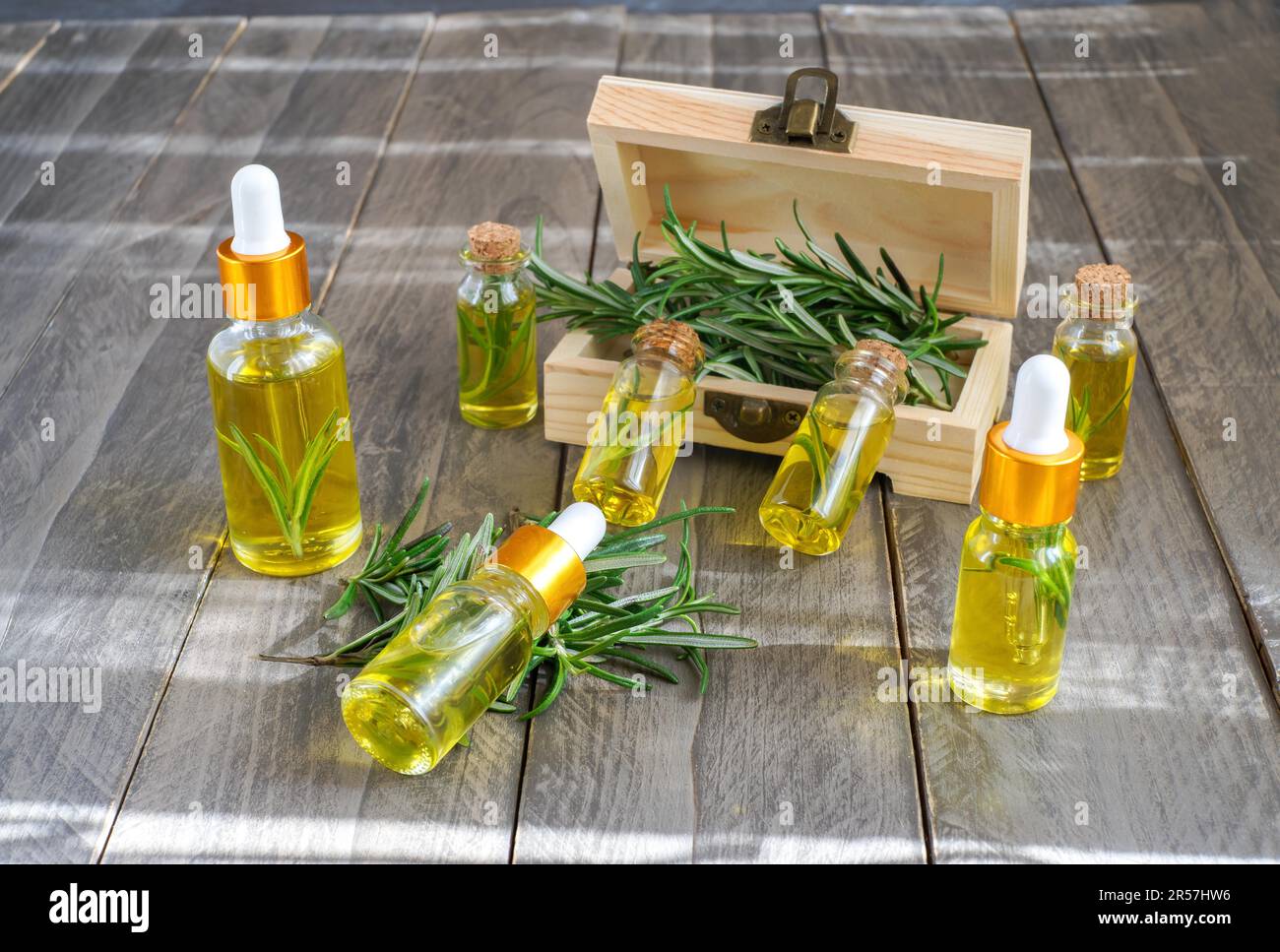 Tropfflaschen mit ätherischem Rosmarinöl in einer Holzbox auf einem Holztisch Stockfoto
