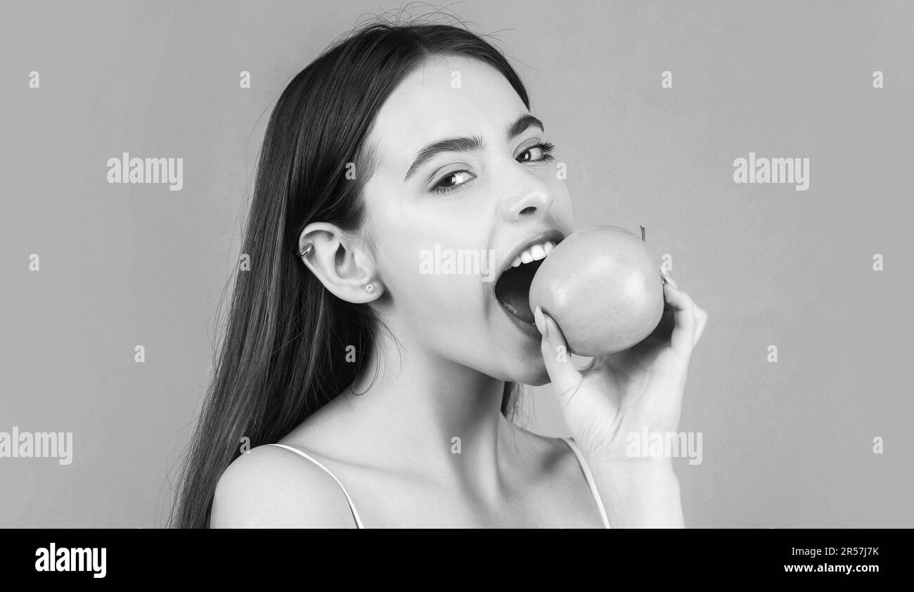 Stomatologisches Konzept. Eine Frau mit perfektem Lächeln, die einen Apfel hält. Gesunde Ernährung. Schwarz auf Weiß Stockfoto