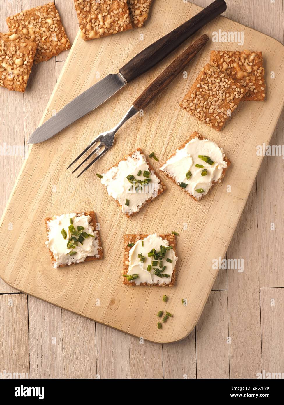 Sesamcracker mit Frischkäse und Schnittlauch auf einem Holzbrett, gesundes Lebensmittelkonzept Stockfoto