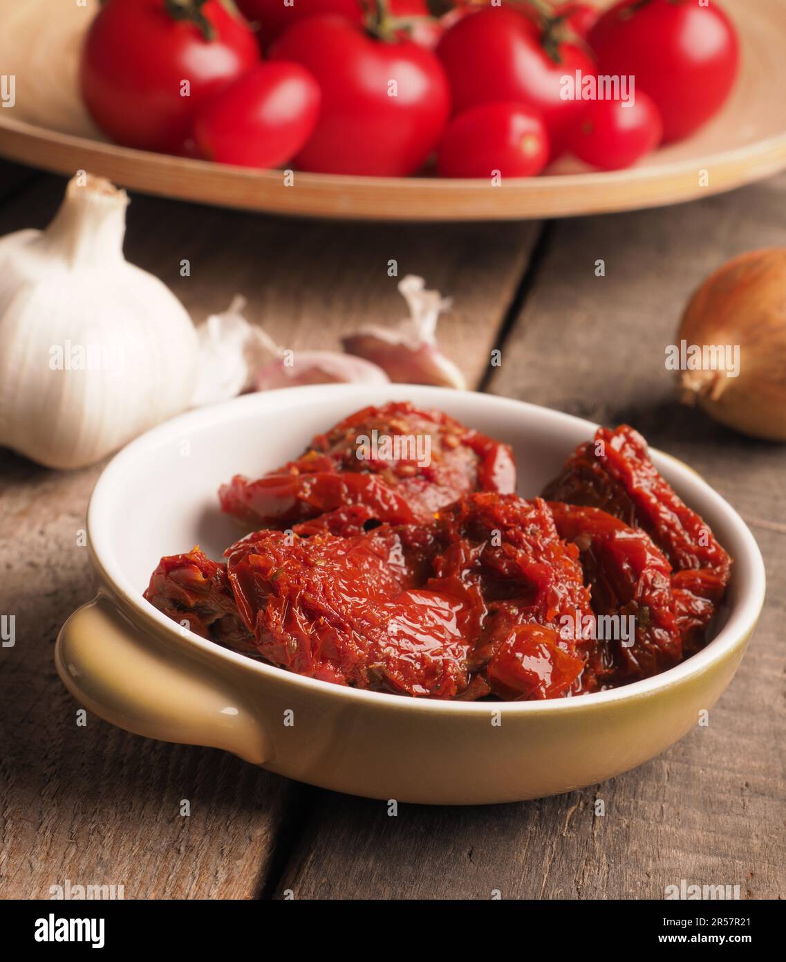 Leckere getrocknete Bio-Tomaten in einer Keramikschale auf einem rustikalen Holztisch, gesunde Lebensmittel oder Zutaten Stockfoto