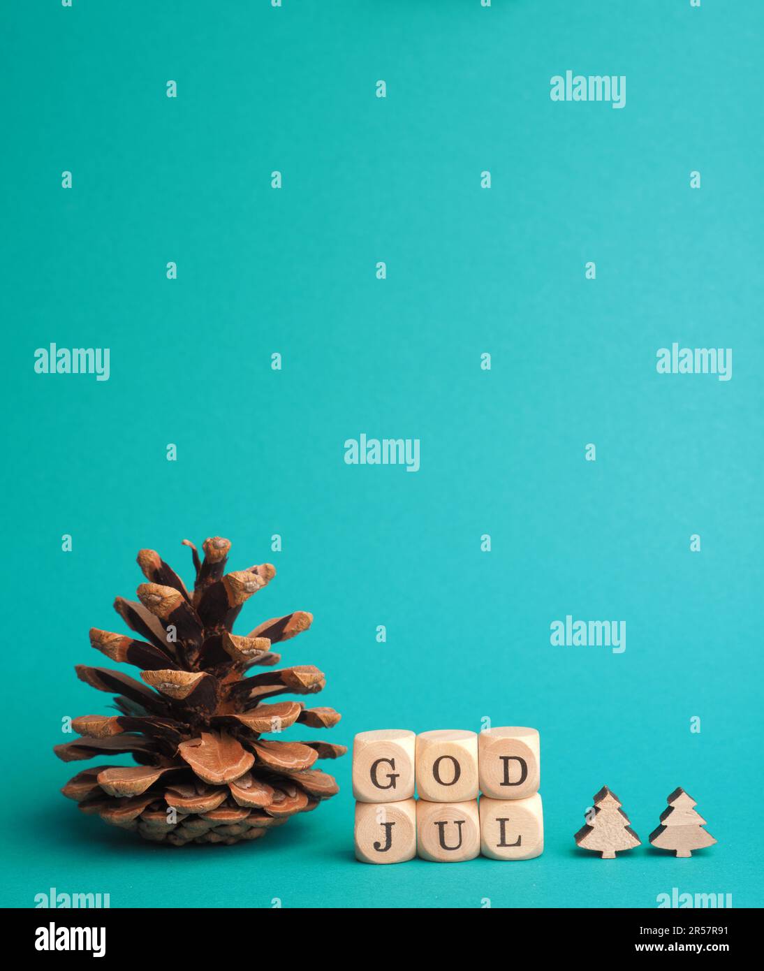 Kleine Holzblöcke mit der Aufschrift God Jul, Scandinavian Merry Christmas, türkisfarbener Hintergrund, minimalistische Weihnachtsdekoration aus Holz Stockfoto