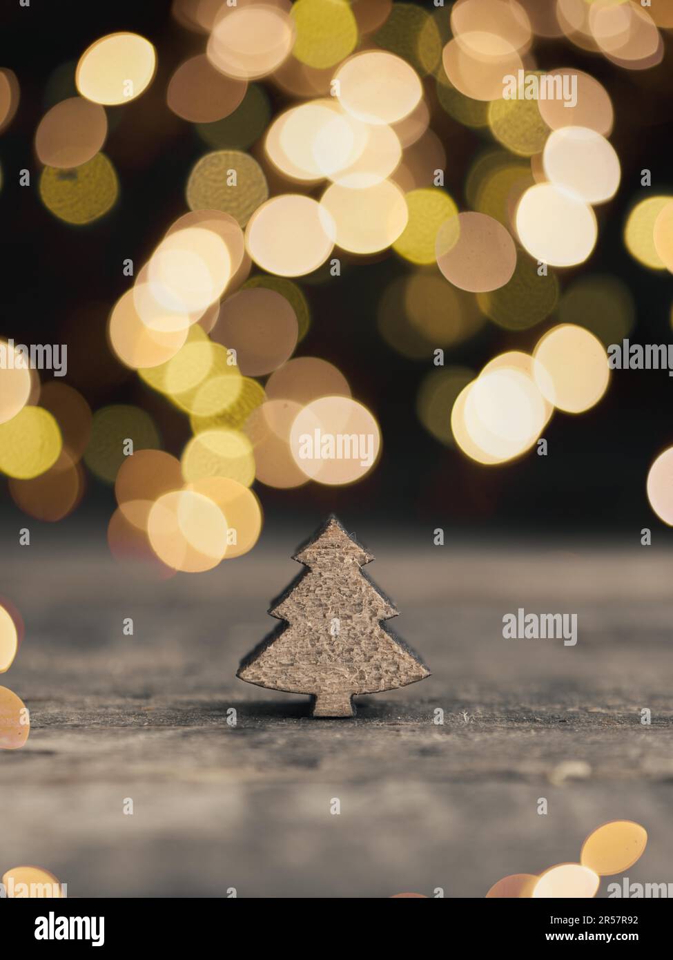 Kleine Holzbaumbauform mit verschwommenen Weihnachtslichtern, traditioneller Weihnachtskartenhintergrund, mit Platz für Text Stockfoto