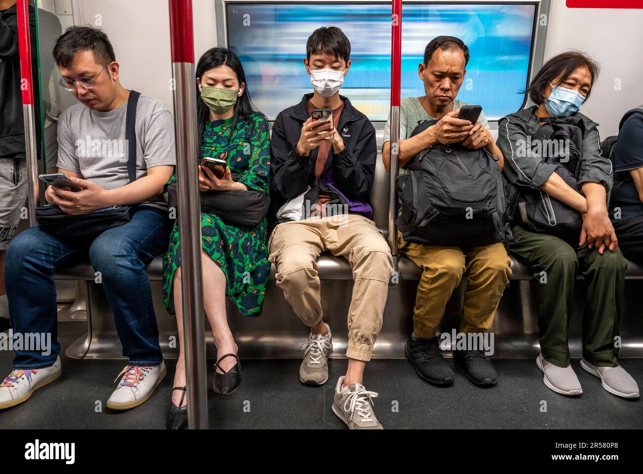 Menschen, die ihre Smartphones in Einem MTR-Zug, Hongkong, China, verwenden. Stockfoto