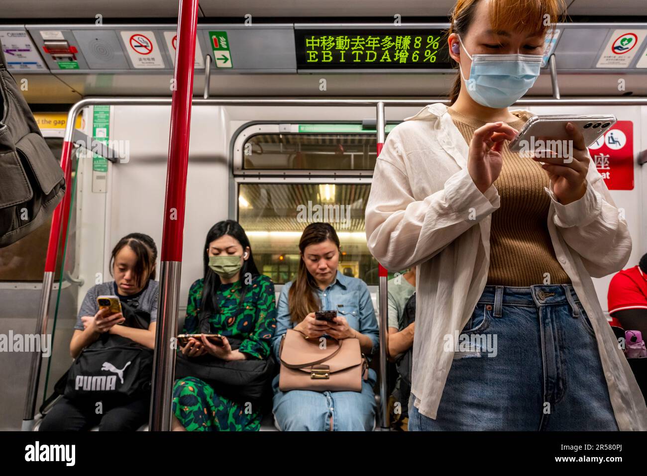 Menschen, die ihre Smartphones in Einem MTR-Zug, Hongkong, China, verwenden. Stockfoto