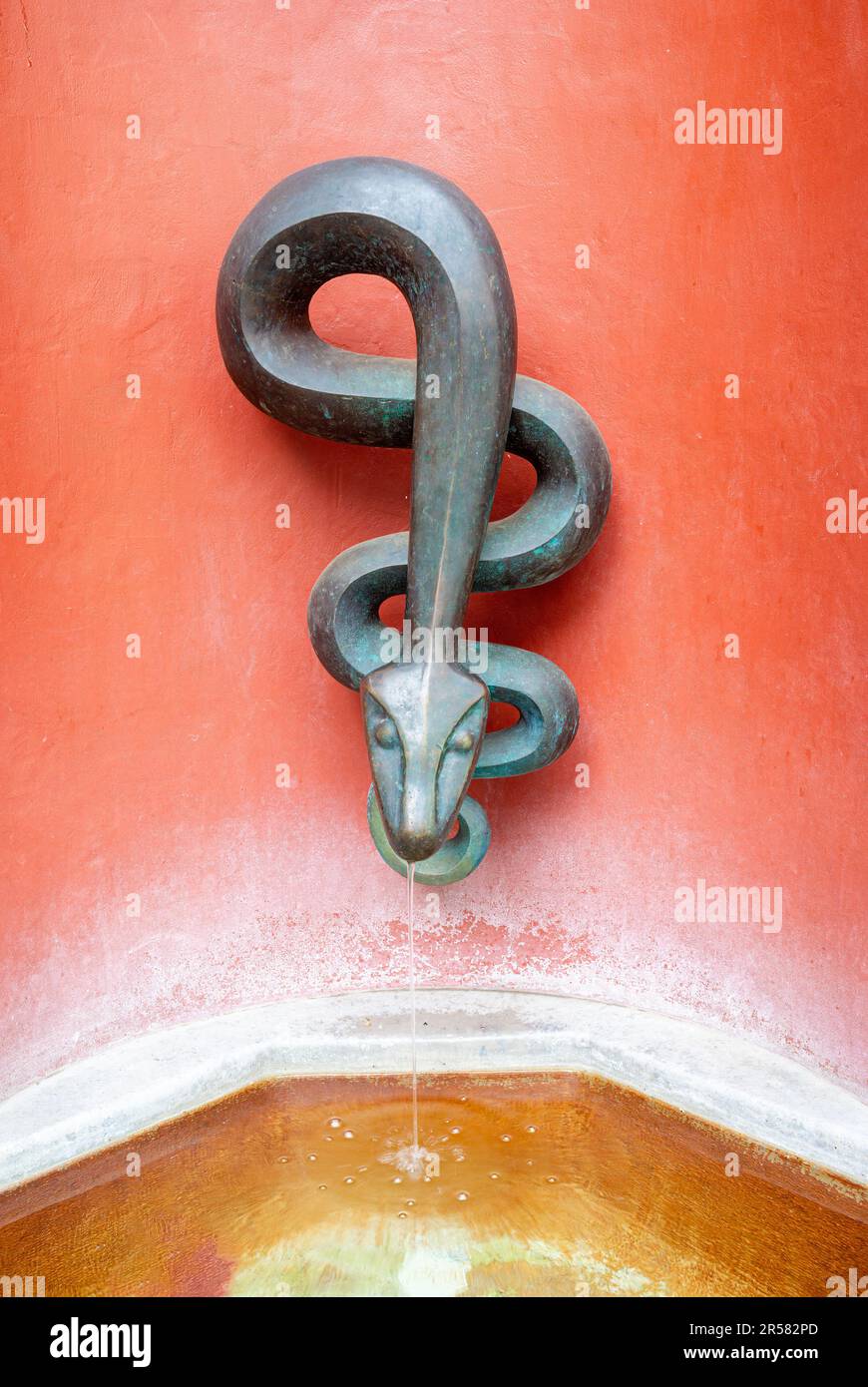 Liestal, Schweiz - 10. Mai 2023: Ein Straßenbrunnen in Liestal mit einem schlangenförmigen Wasserhahn Stockfoto