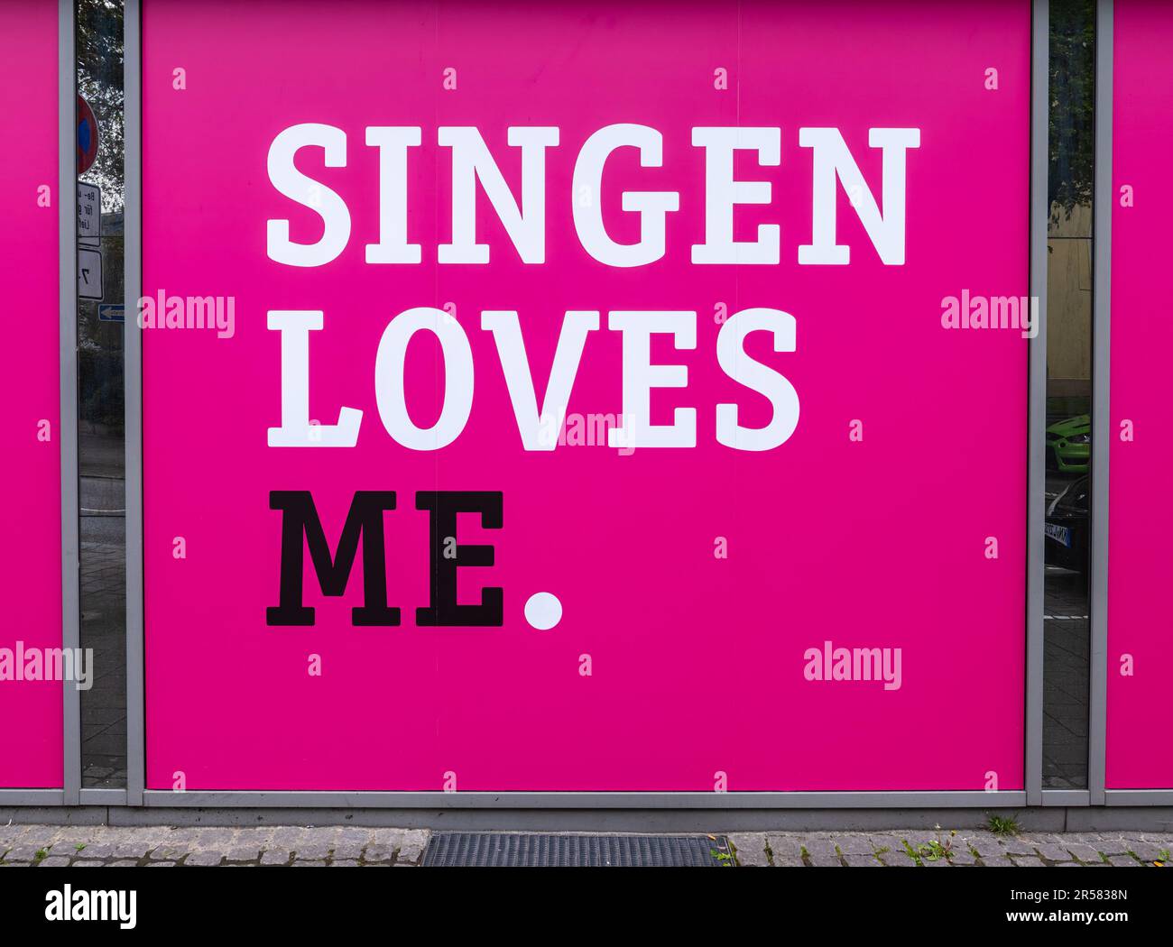 Singen, Deutschland - 1. Mai 2023: Die Inschrift mit dem rosa Hintergrund am Fenster des Modehauses Heikorn in Singen: Singen liebt mich Stockfoto