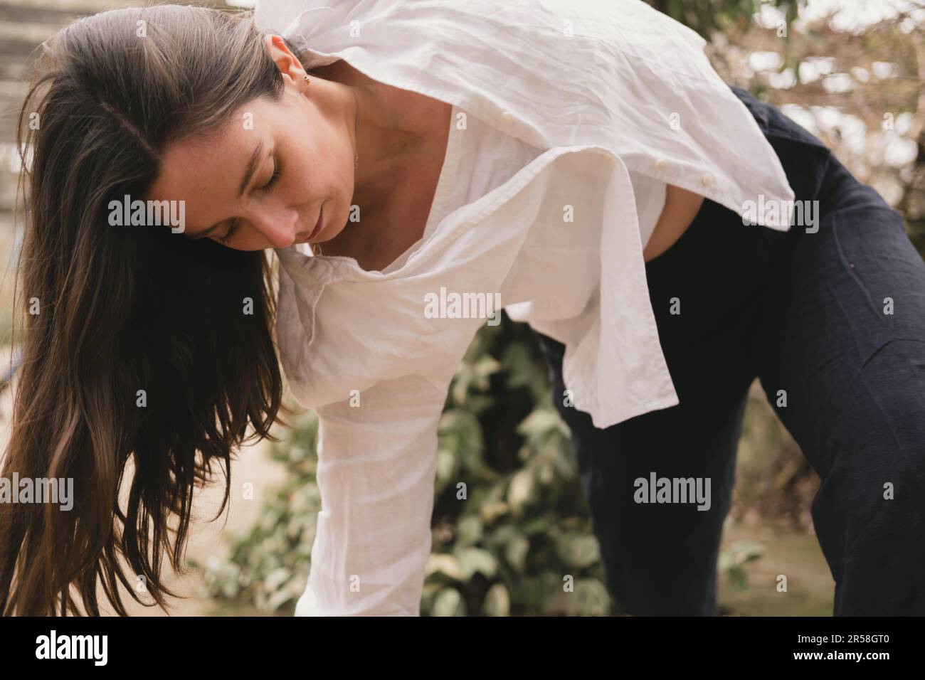 Nahaufnahme einer jungen erwachsenen Yoga-Lehrerin, die sich in ihrem Vinyasa-Fluss bewegt. In schwarz-weiß lässigem Outfit. Außerhalb des Yoga-Trainings. Brünette Stockfoto