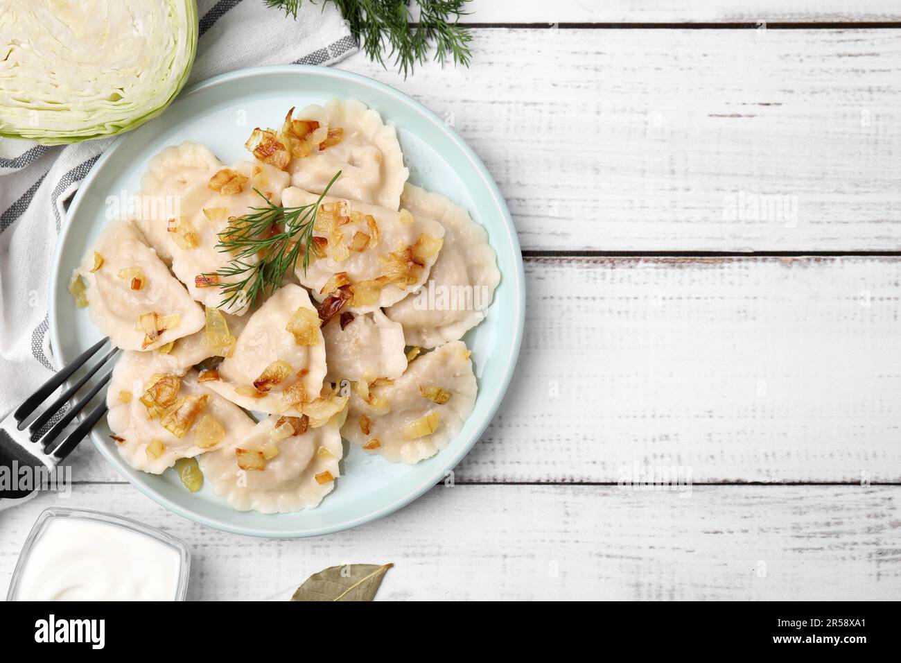 Gekochte Teigtaschen (Varenyky) mit leckerer Füllung, gebratene Zwiebeln und Dill auf Holztisch, flach liegend. Platz für Text Stockfoto