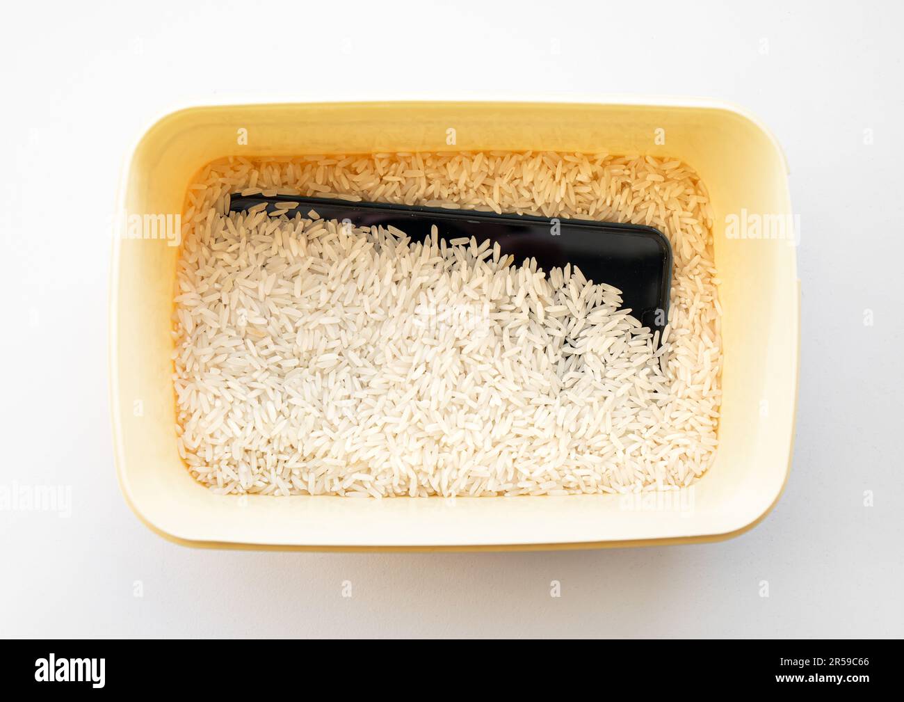 Wasser oder Flüssigkeit beschädigt Smartphone trocken in der Box gefüllt mit ungekochtem weißem Reiswitz, der angeblich Feuchtigkeit absorbiert, aber einige sagen, Reisstaub kann Schaden anrichten. Stockfoto