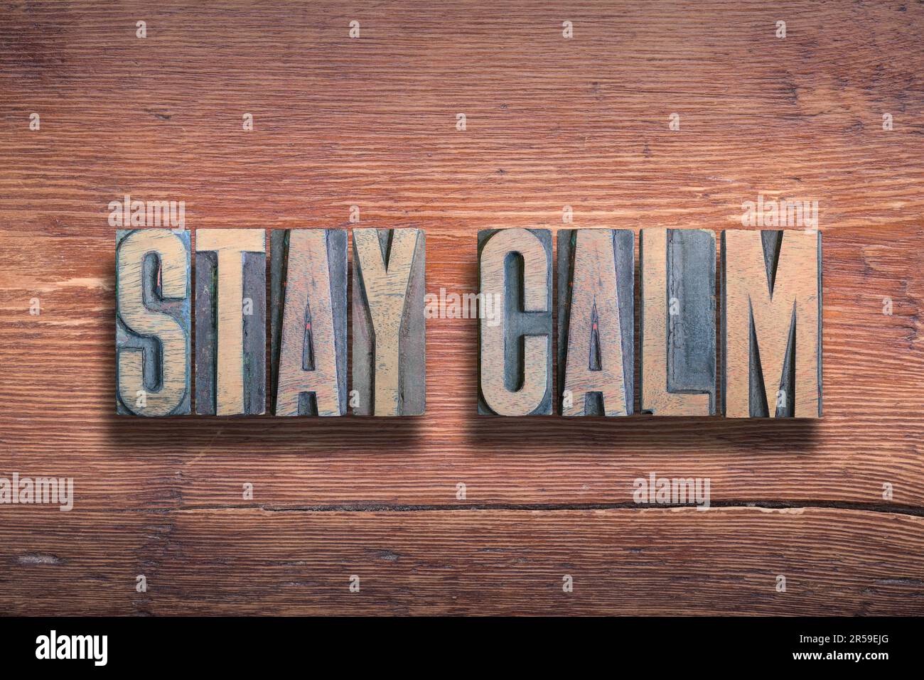 Bleiben Sie ruhig und kombinieren Sie Ihre Worte auf altlackierter Holzoberfläche Stockfoto