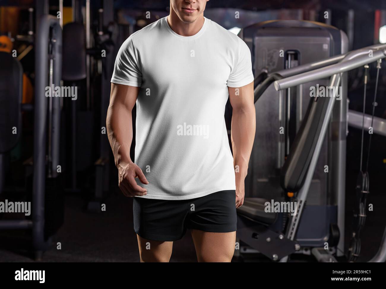 Modell eines weißen Sport-T-Shirts auf einem Sportler im Fitnessstudio, vor dem Hintergrund der Inventur, Trainingsbekleidung, Vorderansicht. Bekleidungsvorlage auf der Stockfoto