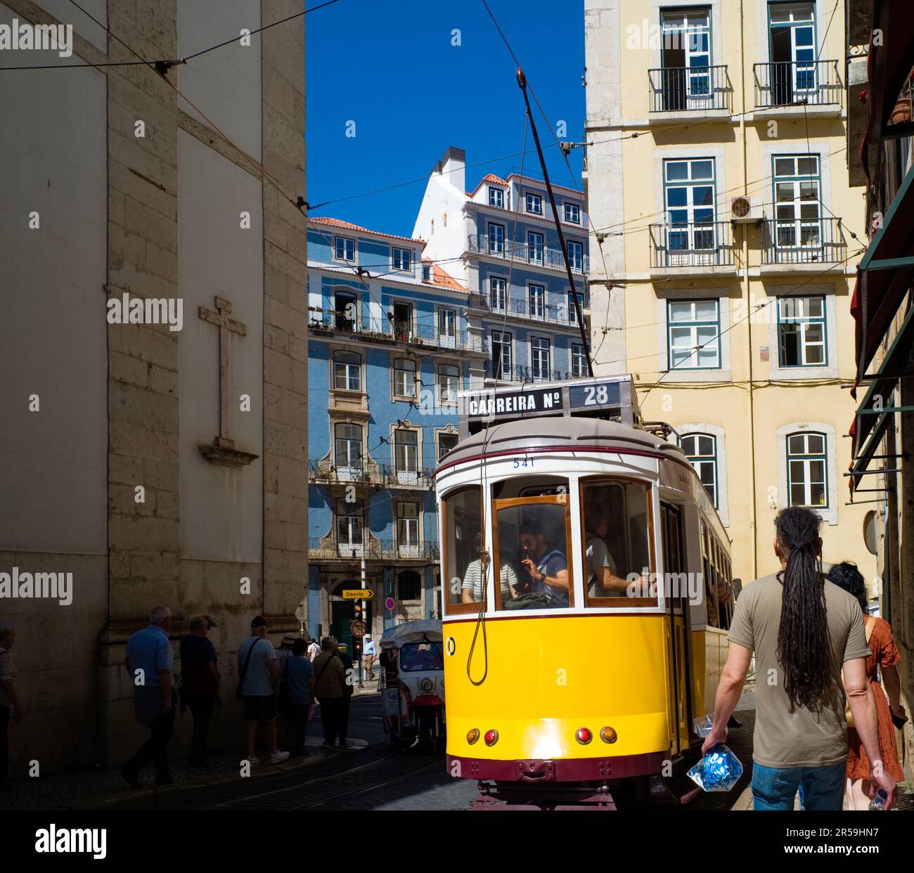 In den engen Straßen Lissabons führt eine berühmte Straßenbahn Nr. 28 sehr nahe an Fußgängerzonen vorbei Stockfoto