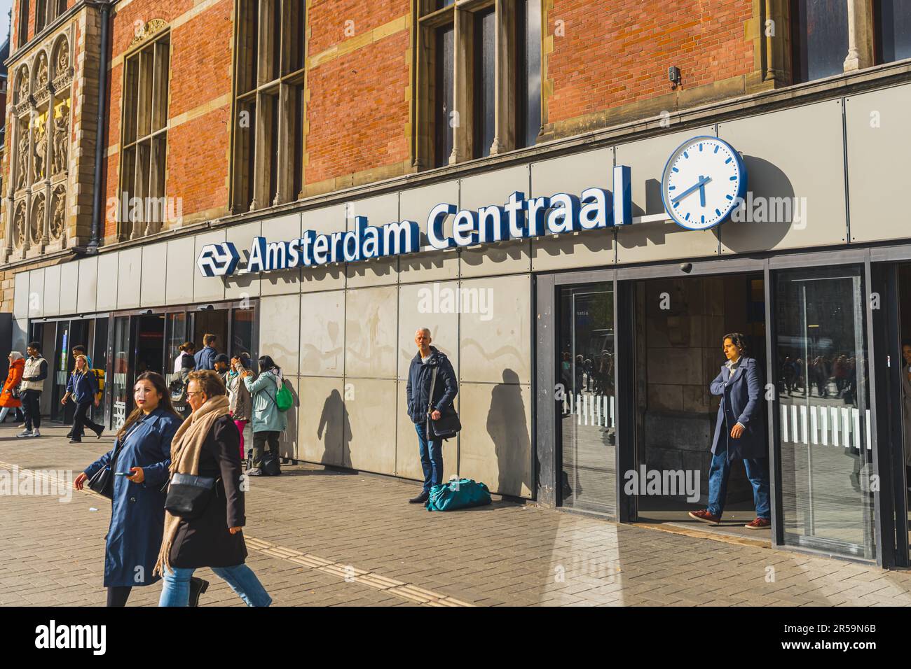 04.18.2023 Amsterdam, Holland. Internationaler Bahnhofsknotenpunkt Amsterdam Centraal, Touristen betreten den Bahnhof an sonnigen Tagen. Hochwertiges Foto Stockfoto