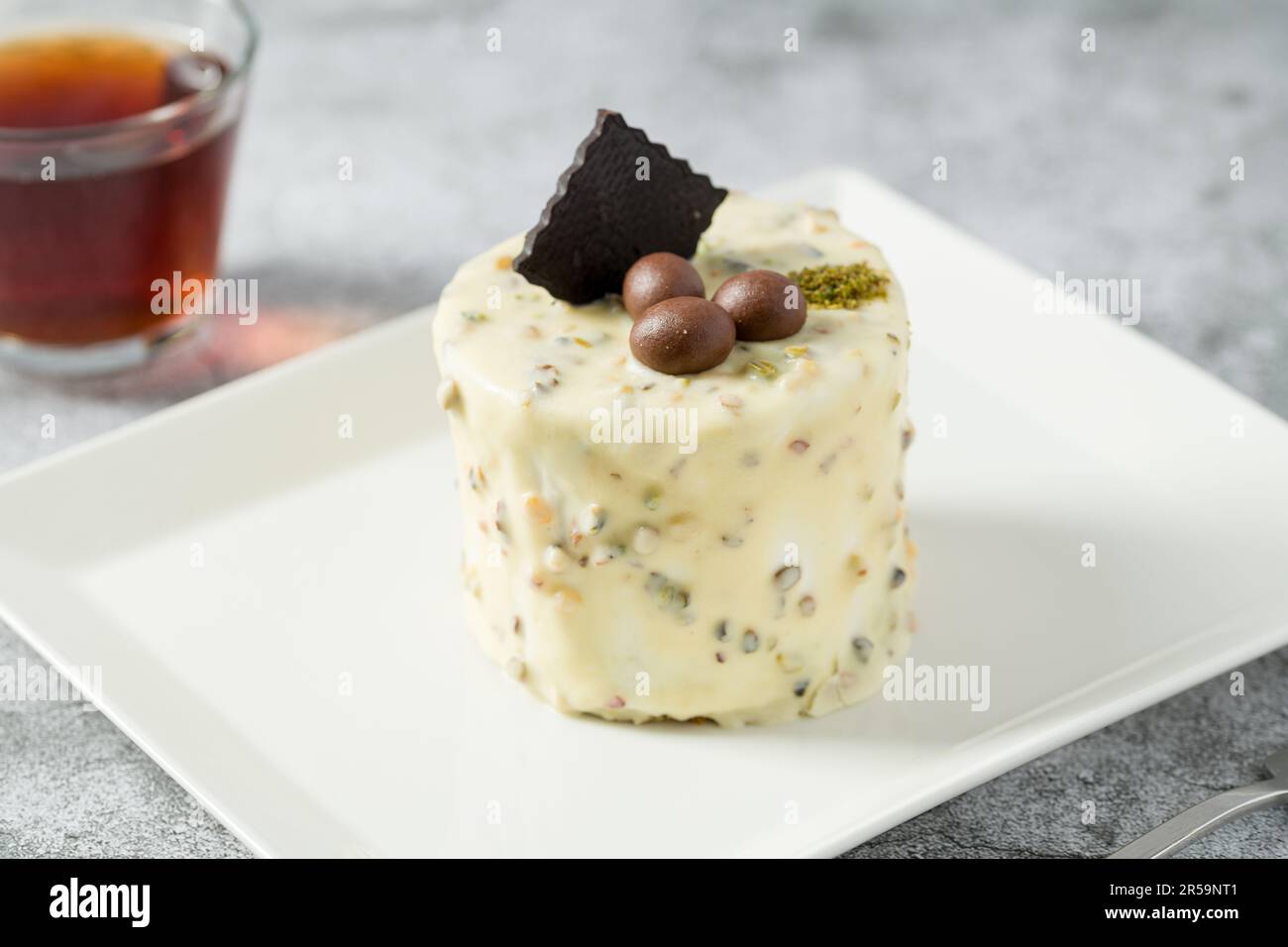 Ein-Personen-Minikuchen mit Pistazien und weißer Schokolade auf einem weißen Porzellanteller Stockfoto