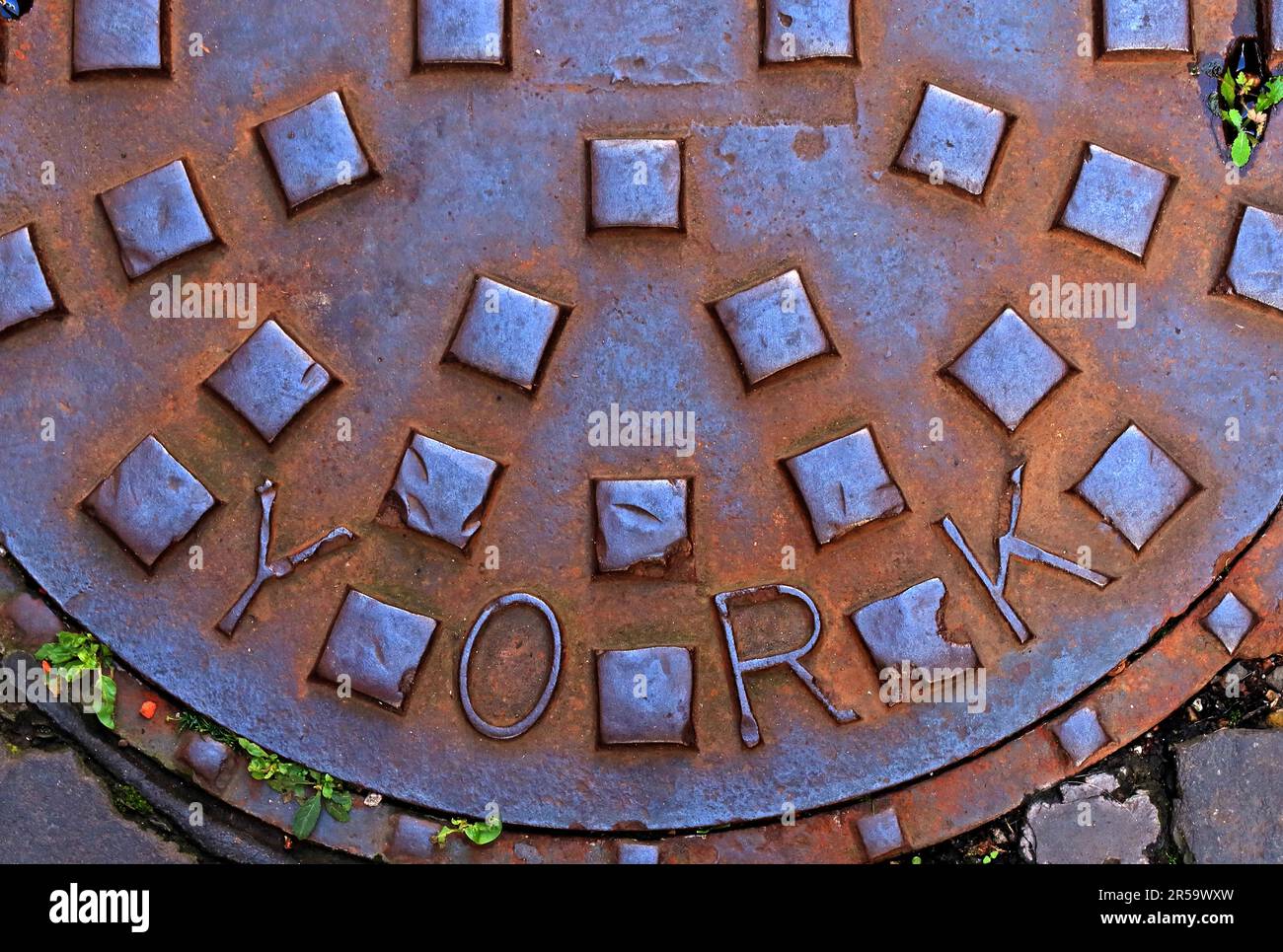 Nahaufnahme eines rostigen gusseisernen Straßengitters in York, das verwittertes Metall, geometrische Muster und alternde städtische Infrastruktur zeigt, England, Großbritannien. Stockfoto