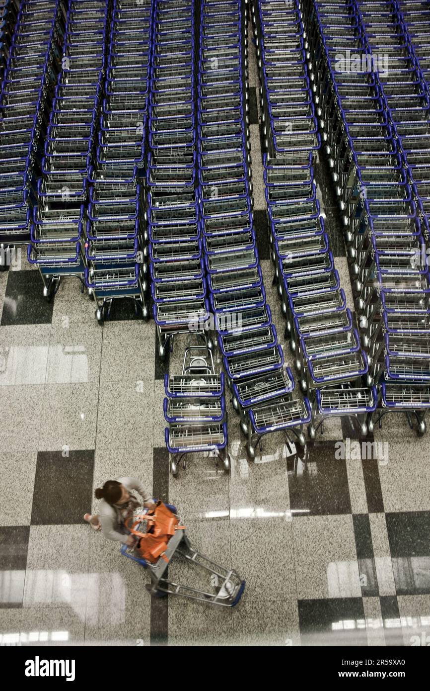 Ein Reisender, der einen Flughafen-Trolley am Flughafen Changi, Singapur, bekommt. Stockfoto