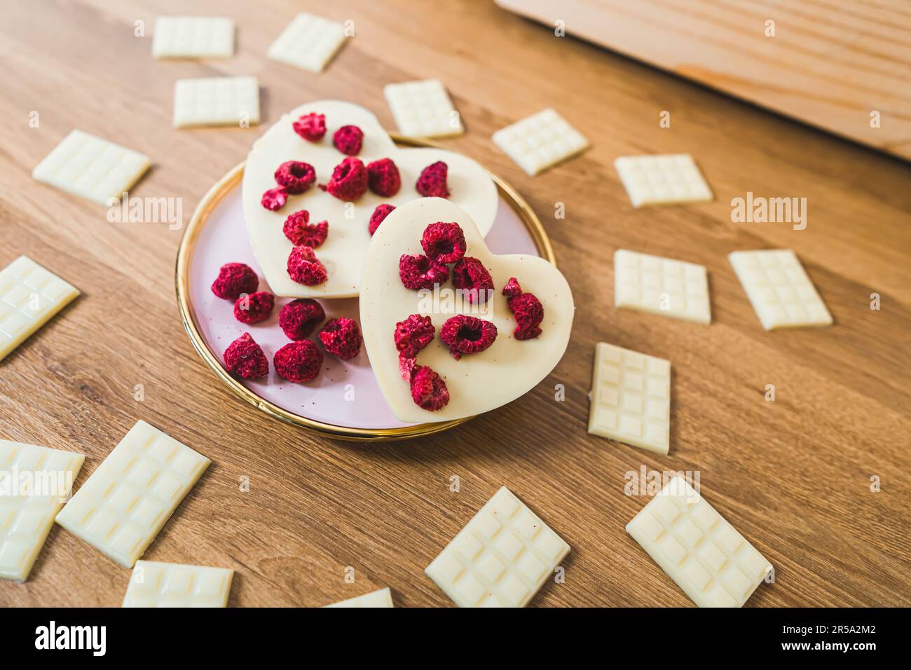Handgefertigte, herzförmige weiße Schokolade und Schokoriegel mit Himbeeren. Hochwertiges Foto Stockfoto