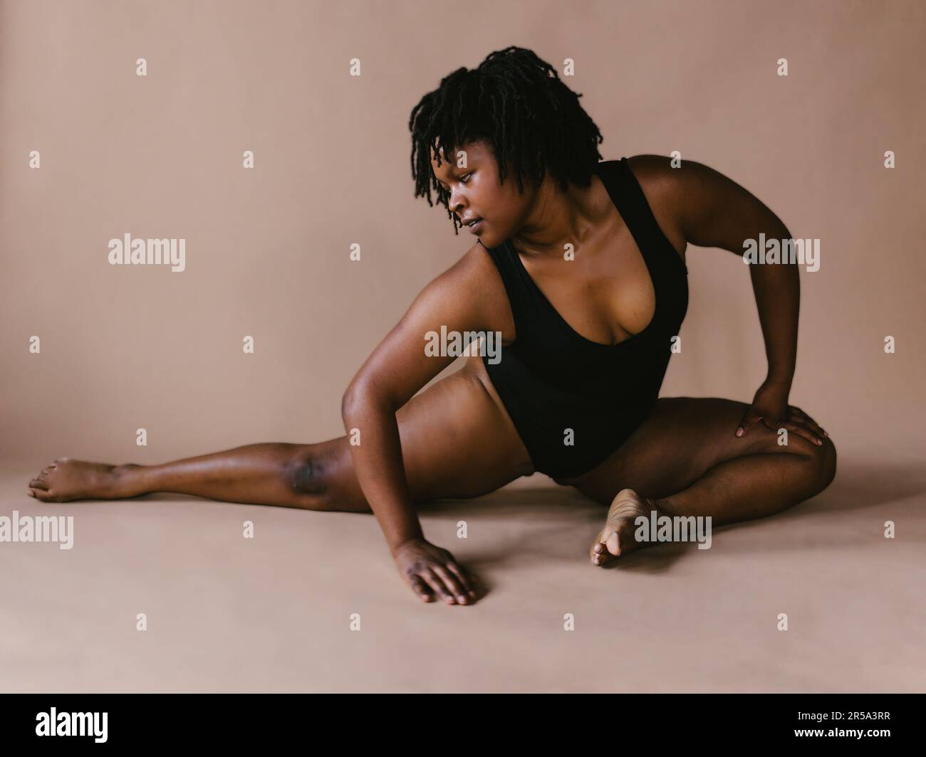 Schwarze Tänzerin in halbgeteilter Stretchtanz-Pose im Studio Stockfoto