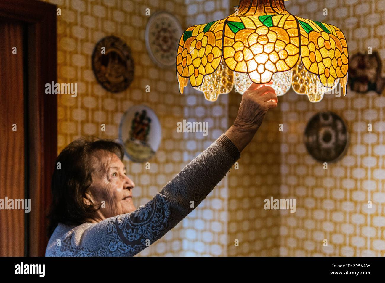 Alte Dame, die eine Glühbirne in eine Lampe steckt Stockfoto