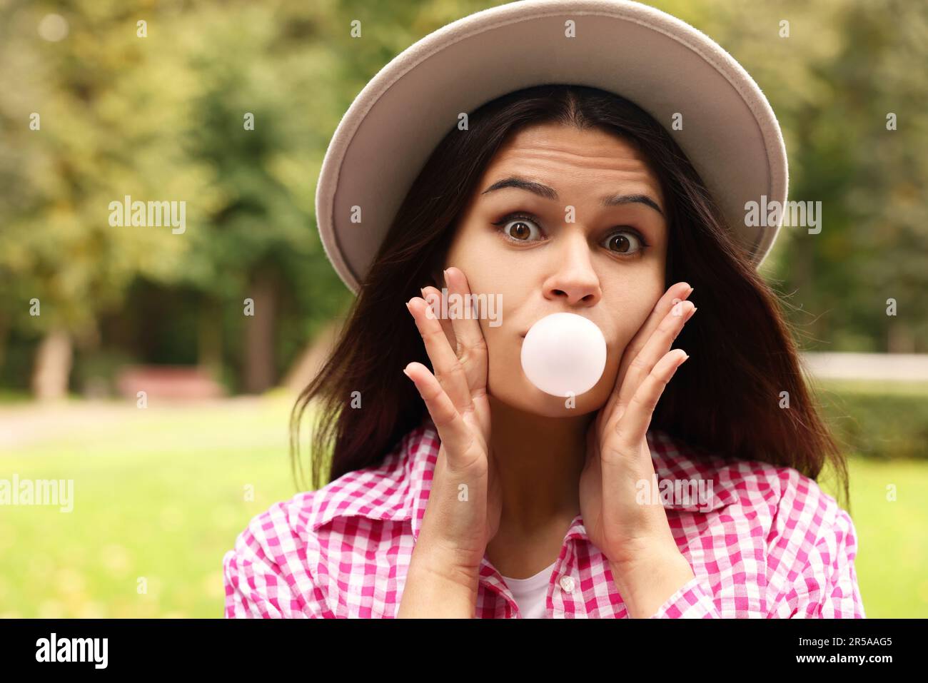 Schöne junge Frau, die draußen Kaugummi bläst Stockfoto