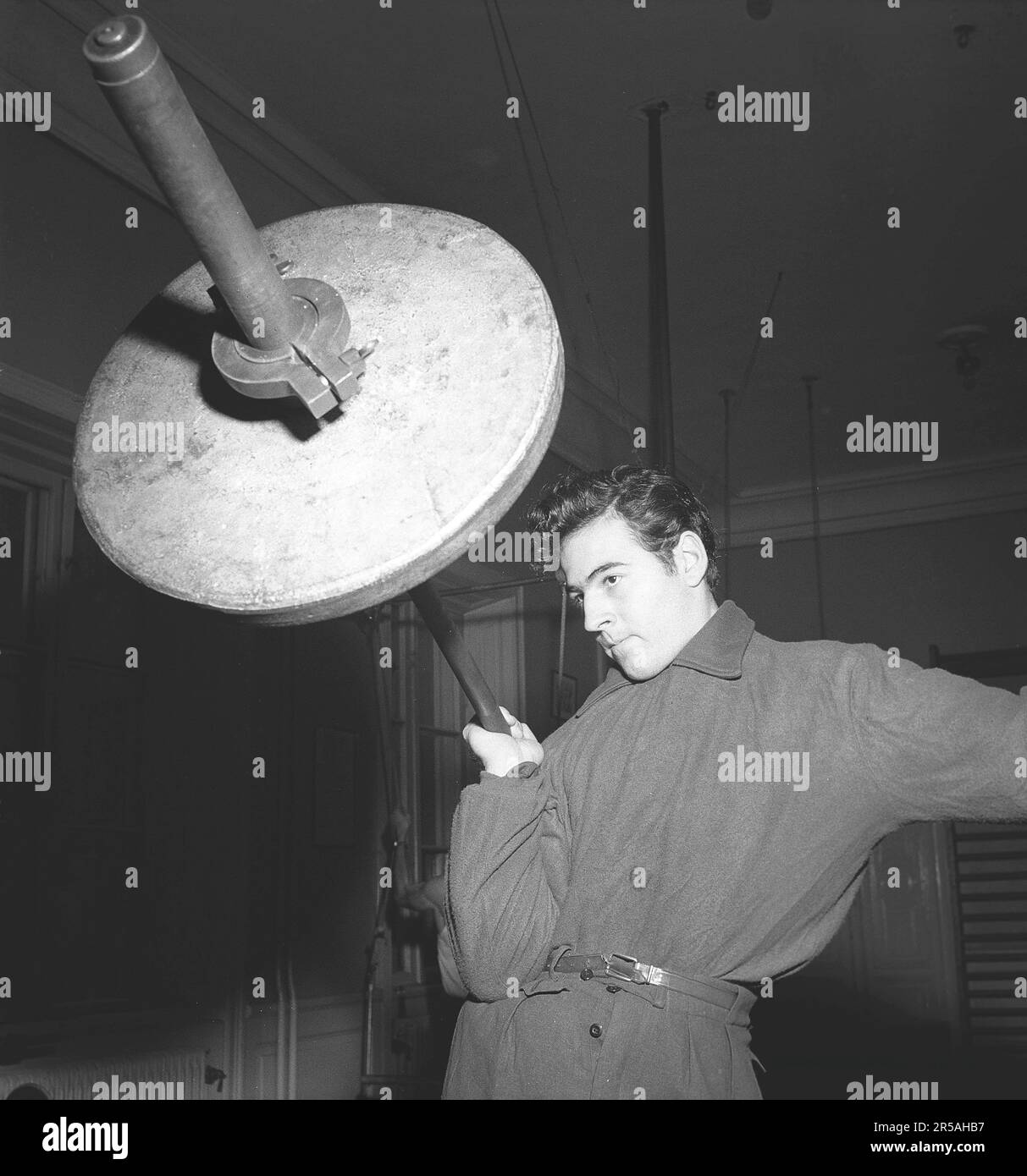 Mann in den 1940er. Ein junger Starker trainiert mit einer Hantel. Man sieht, wie er die schweren Gewichte mit nur einer Hand hält. Schweden 1946. Kristoffersson Ref. X111-1 Stockfoto