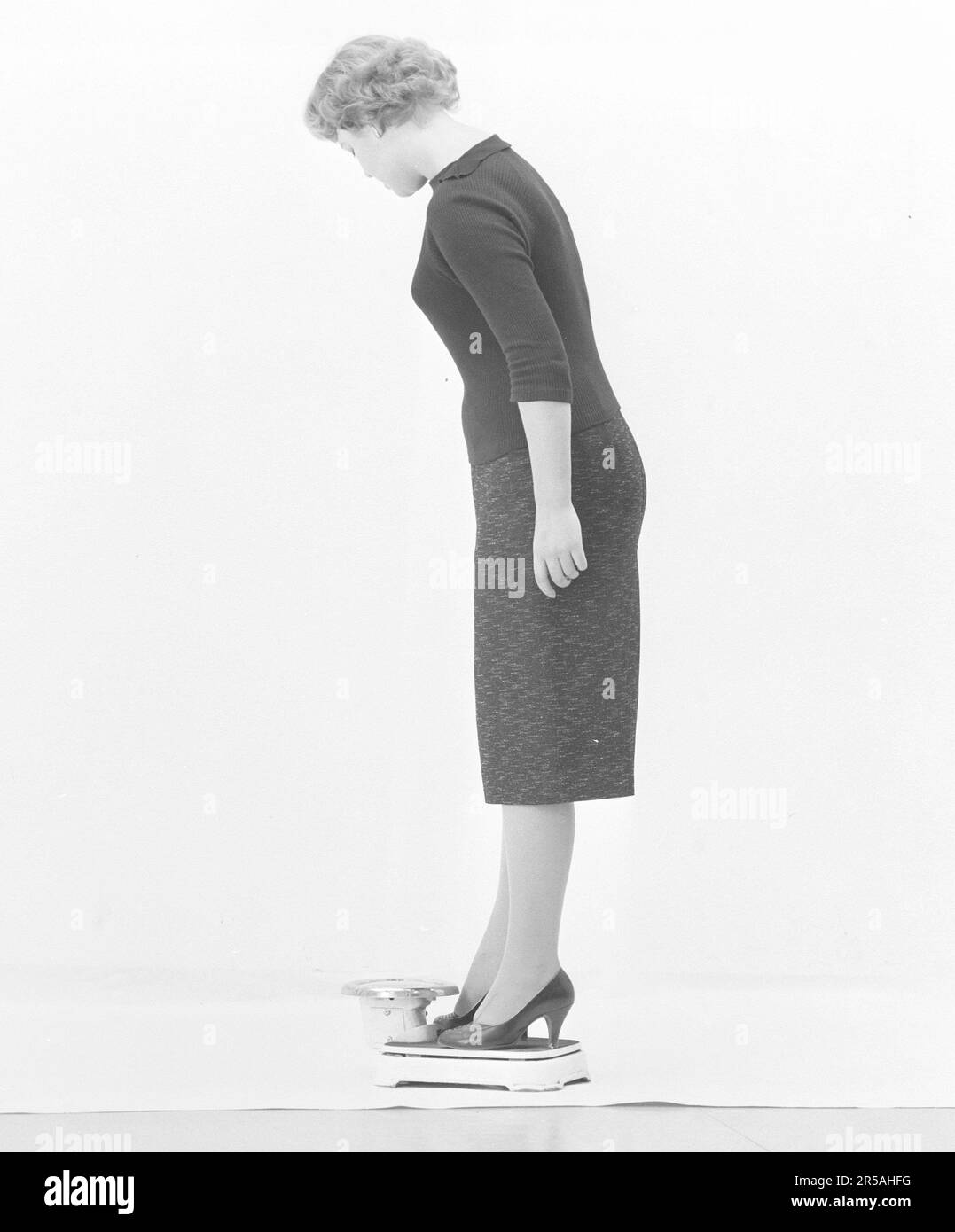 Frau in den 1950er. Sie steht und wiegt sich auf einer Waage. Schweden märz 1959 Stockfoto