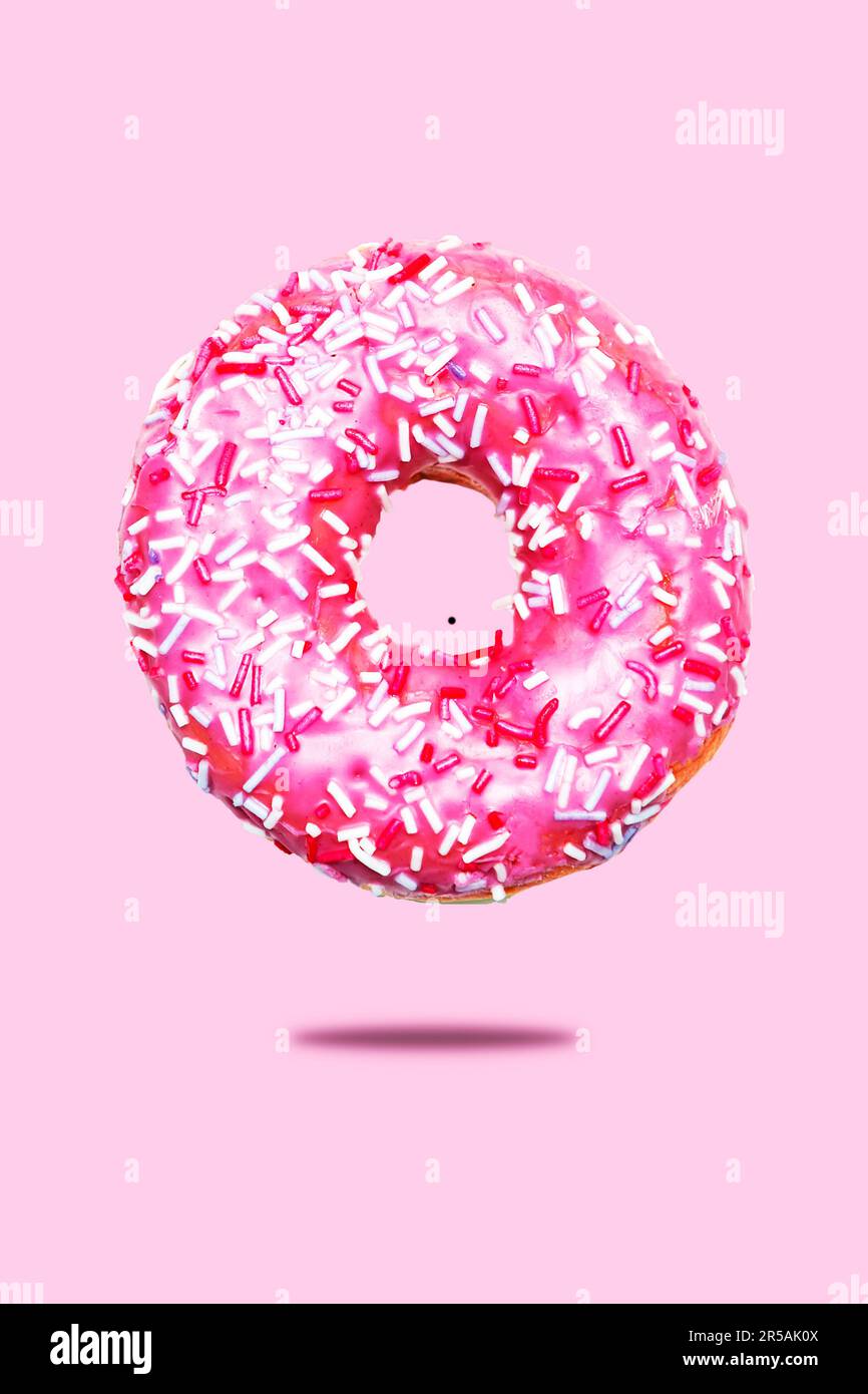 Donut mit rosa Glasur und Streuseln. Isoliert auf pinkfarbenem Hintergrund. Stockfoto