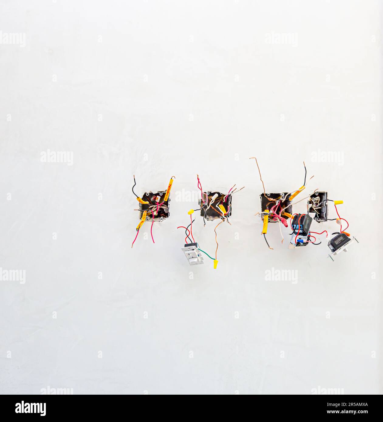 Eine Innenwand mit mehreren Lichtschaltern ohne Abdeckplatten Stockfoto