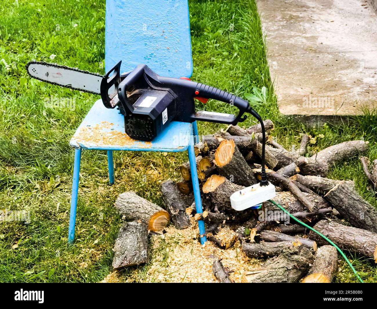 Elektrische Kettensäge und Schnittholz während der saisonalen Arbeiten im  Garten und Schneiden von Bäumen für Brennholz Stockfotografie - Alamy