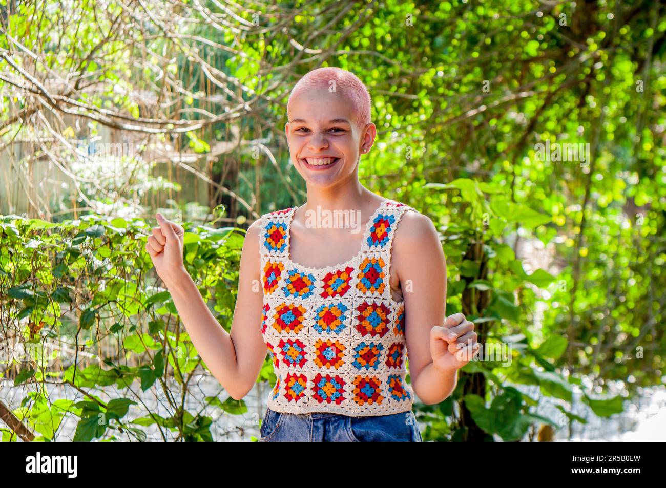 Porträt eines Mädchens mit sehr kurzen Haaren, rosa gestrichen. Porträt eines Mädchens in Häkelkleidung. Stockfoto