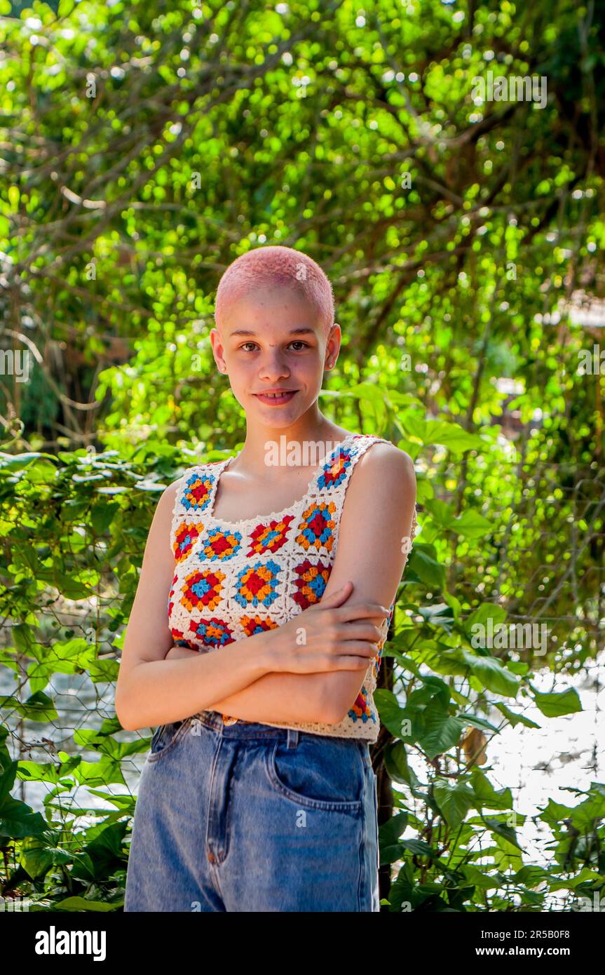 Porträt eines Mädchens mit sehr kurzen Haaren, rosa gestrichen. Porträt eines Mädchens in Häkelkleidung. Stockfoto