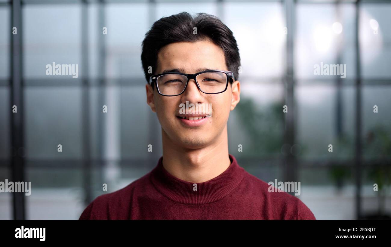 Ein hübscher junger asiatischer Mann, der in einem roten Pullover lächelt und in die Kamera lächelt Stockfoto