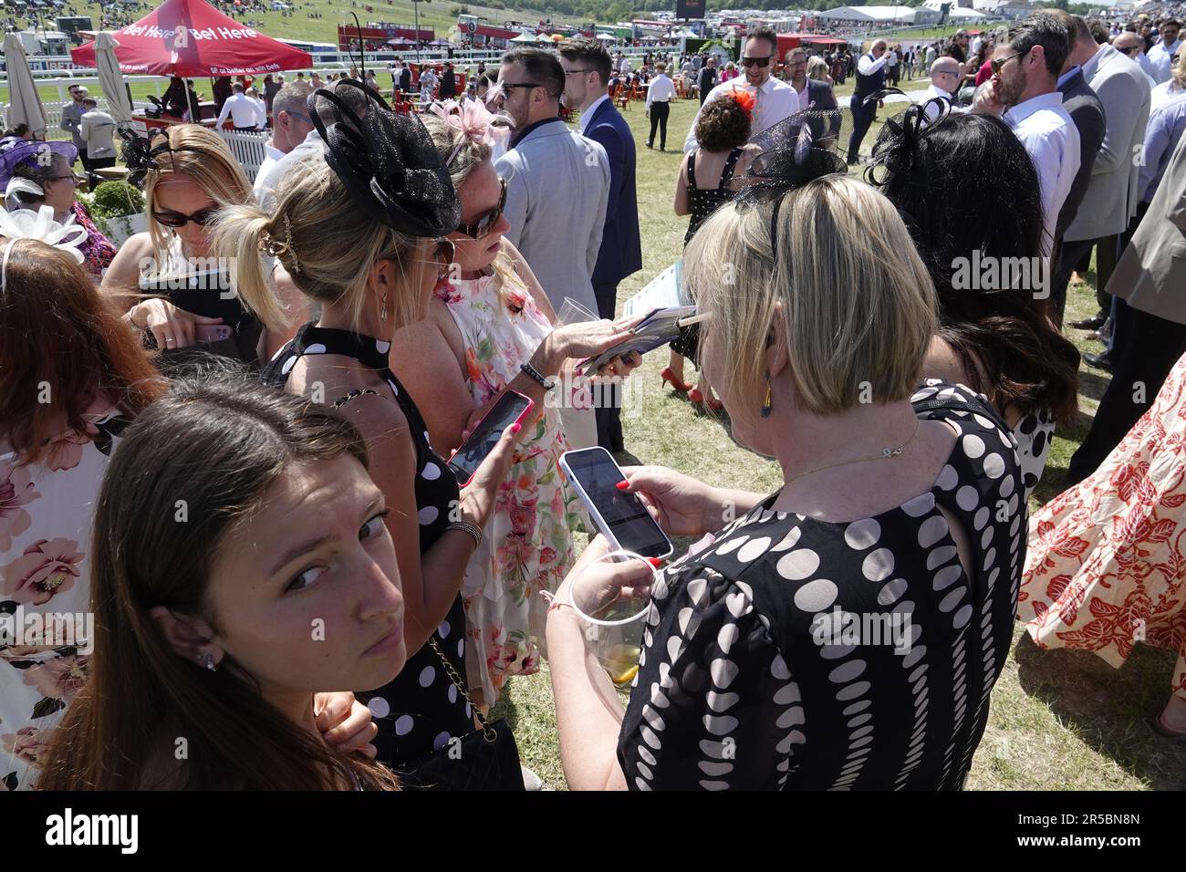 Epsom, Surrey, Großbritannien. 2. Juni 2023. Szenen in den Betfred Oaks, während des Betfred Derby Festivals - hier: Stilvolle Rennfahrer vergleichen Wetten auf ihre iPhones in der Sonne vor dem Hauptrennen des Tages. Credit: Motofoto/Alamy Live News Stockfoto