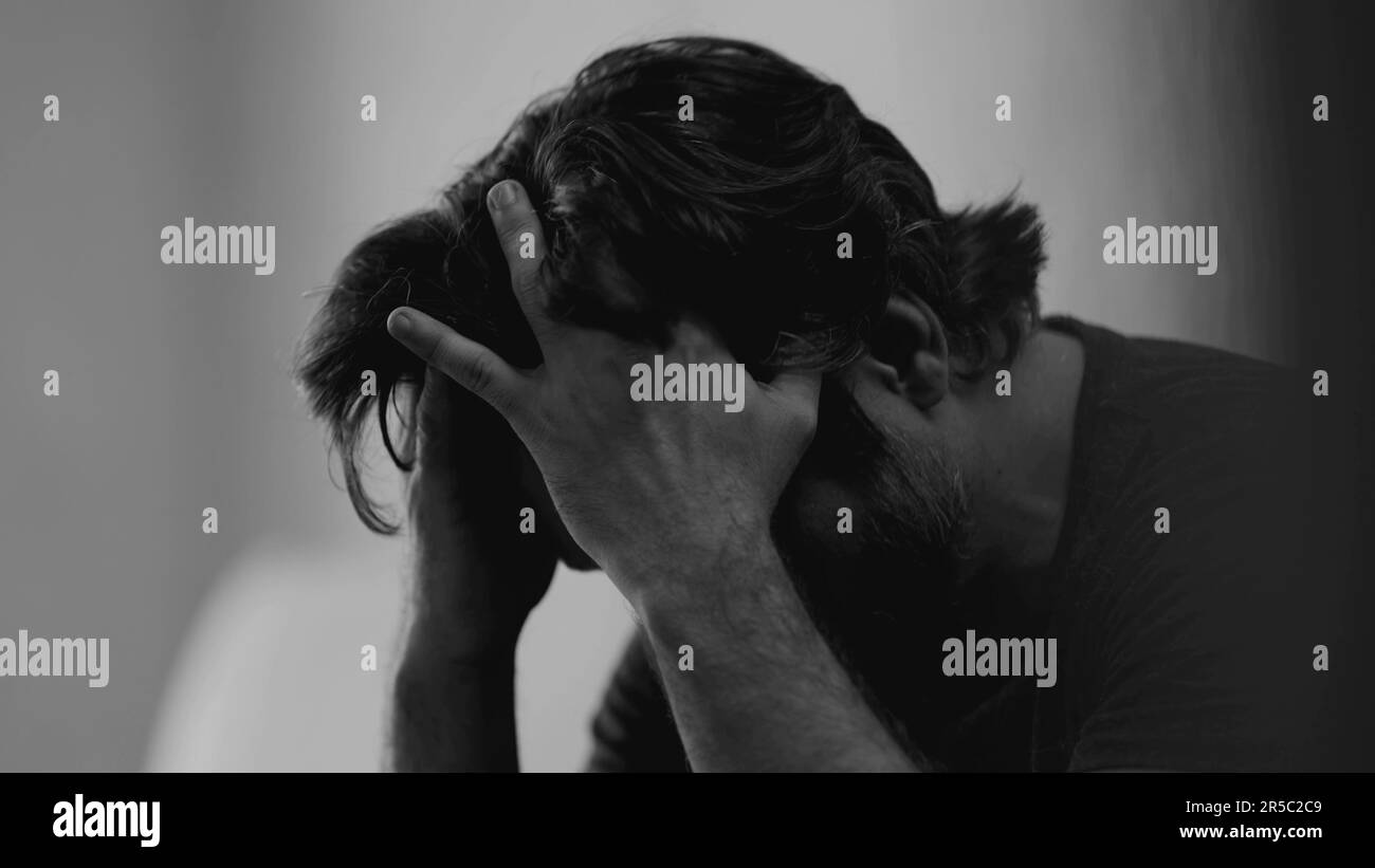 Dramatisch depressiver junger Mann mit emotionalem Schmerz. Düsteres Nahtgesicht eines Mannes in 30s Jahren, der Traurigkeit empfindet und sich in monochromatischem Schwarz verirrt hat Stockfoto