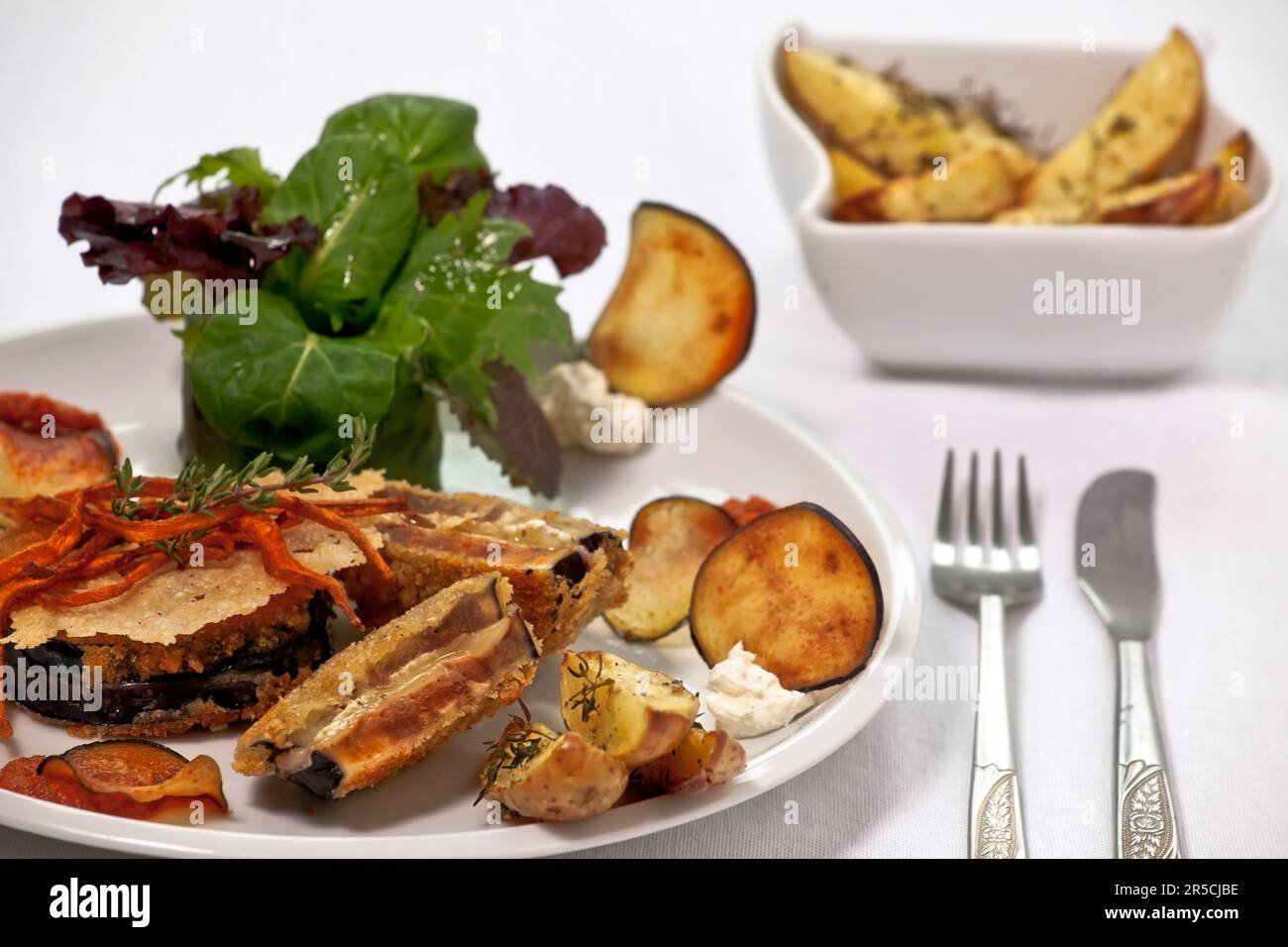 Aubergine Cordon Bleu, gefüllt mit schweizer Käse und rotem Pesto, serviert mit Thymiankartoffeln, vegetarisch, Besteck Stockfoto