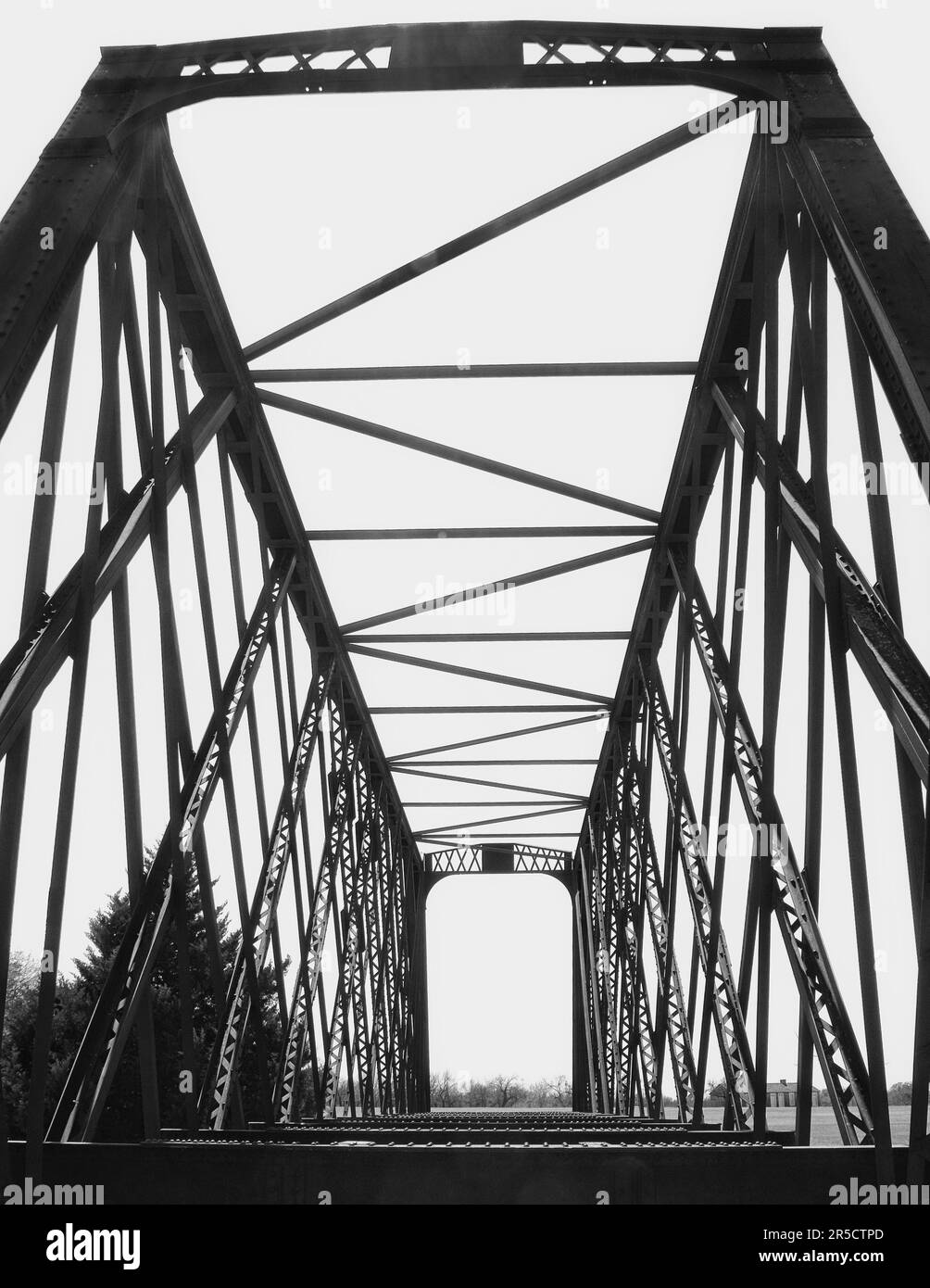 Schwarzweißbild einer Stahlgitterbrücke im Fort Richardson State Park außerhalb von Jacksboro, Texas. Dunkle Kontraste, weißer Himmel. Stockfoto