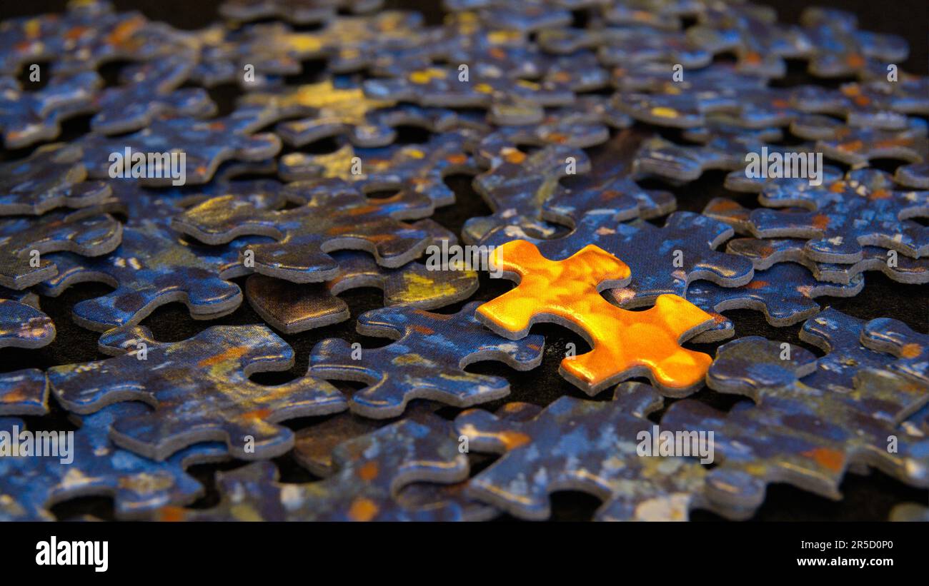 Unpassendes Puzzleteil - orangefarbenes Puzzleteil auf einem Haufen blauer Puzzleteile Stockfoto