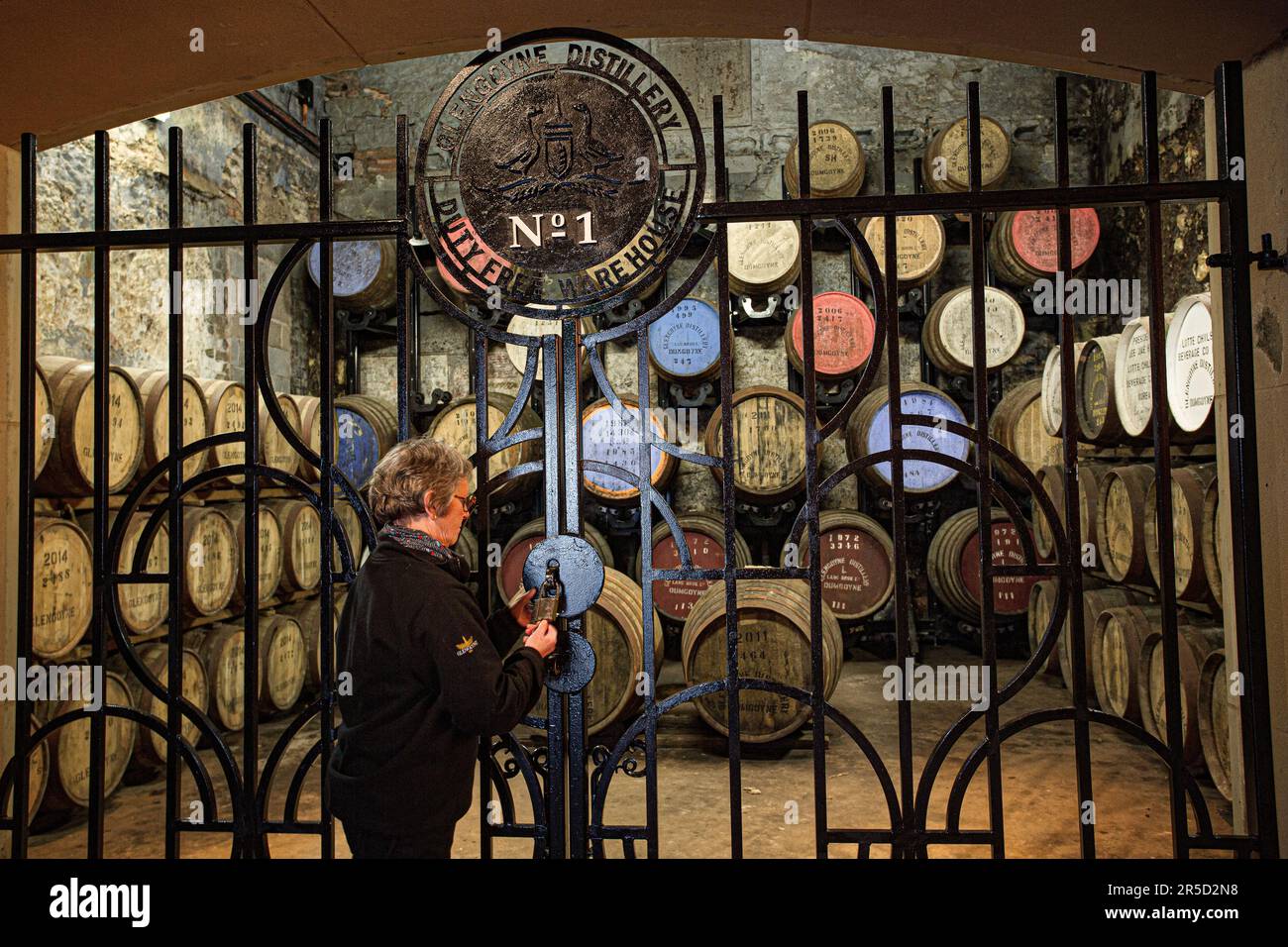 Der Reiseleiter für die Warehouse No. 1 Destillerie öffnet das Iron Gate in der Glengoyne Distillery - Dumgoyne, Stirlingshire, Schottland, Großbritannien. Stockfoto