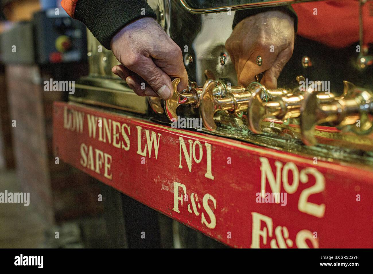 Still man überprüft den Alkoholgehalt im Spirit Safe der Springbank Distillery Campbeltown, Schottland Stockfoto