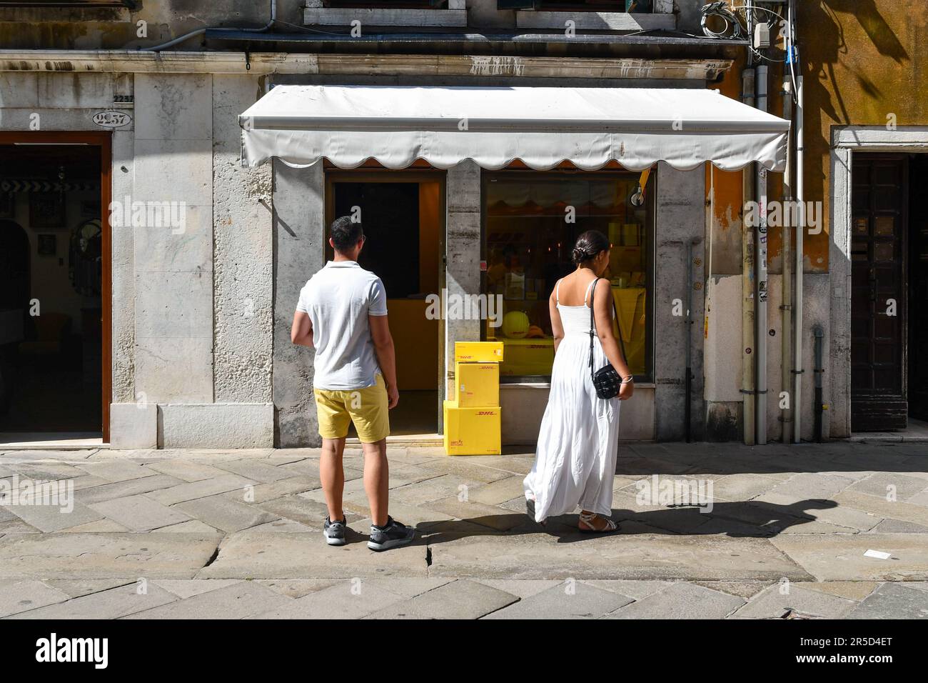 Ein paar Touristen vor einem geschlossenen Geschäft in Strada Nova, Sestiere von Cannaregio, an einem sonnigen Sommertag, Venedig, Veneto, Italien Stockfoto
